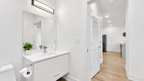 A modern bathroom with a white vanity, a large mirror, and a toilet.