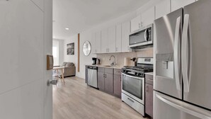 Una cocina moderna con electrodomésticos de acero inoxidable, lavavajillas y un comedor con mesa y sillas.