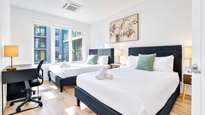A hotel room with two beds, a desk, and a chair.