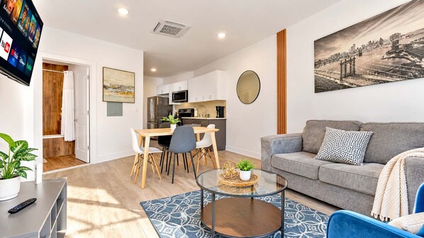 Un salon moderne comprenant un canapé, une table basse et un coin repas avec des chaises.