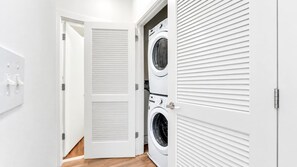 A laundry room with a white door, a washing machine, and a dryer. - Stylish 1BD Near Schuylkill River | Fits 2 Comfort (Philadelphia)