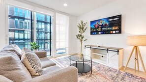 A modern living room with a sofa, coffee table, and a TV mounted on the wall. - Stylish 1BD Near Schuylkill River | Fits 2 Comfort (Philadelphia)