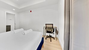A hotel room with a bed, a desk, and a chair.