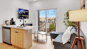 A modern apartment with a kitchen, a dining area, a sofa, and a balcony with a city view. - Comfy 1BR Retreat by Liberty Bell | Perfect for 2 (Philadelphia)