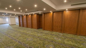 A large room with patterned carpet, wooden paneling with geometric designs, and recessed ceiling lighting. - Al Massa Grand Hotel (Makkah)