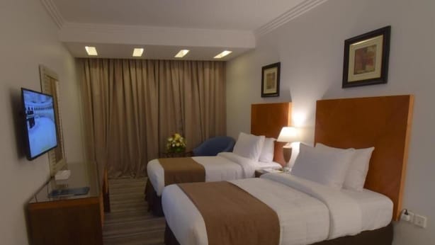 A hotel room with two beds, a television, a desk, and a window with curtains. - Al Massa Grand Hotel (Makkah)