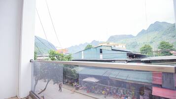 Un balcón con vista a un mercado callejero y montañas al fondo.