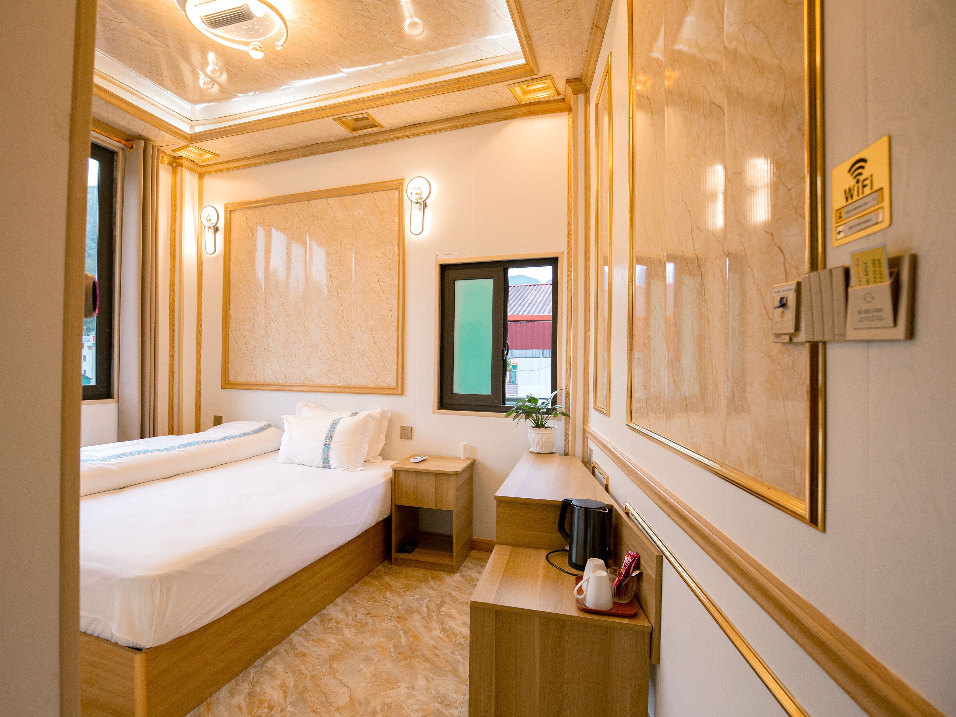 A hotel room with a bed, bedside table, nightstand, and a window with a view.