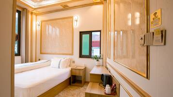A hotel room with a bed, bedside table, nightstand, and a window with a view.