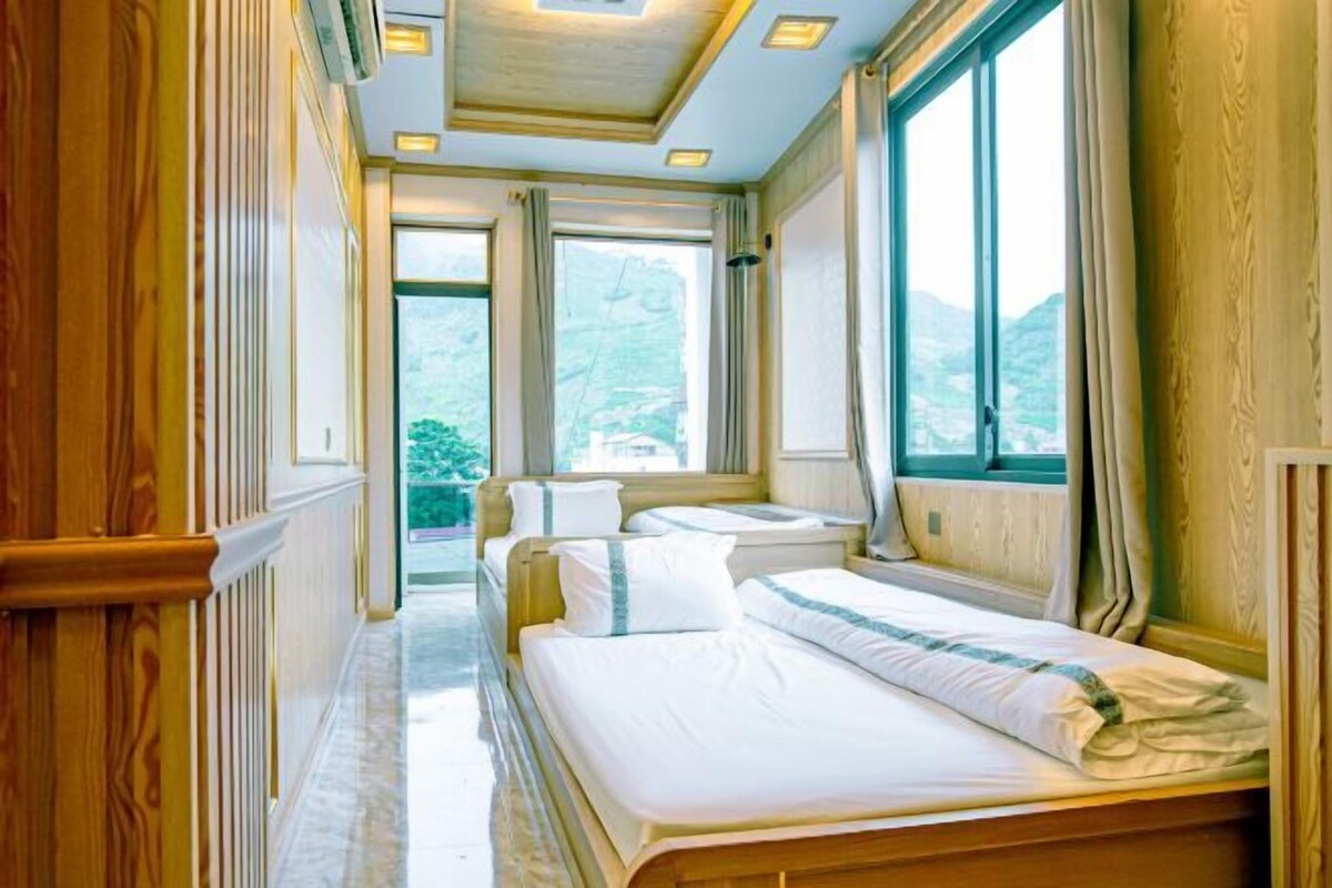 A hotel room with a large bed, two bedside tables, and a window with a mountain view.