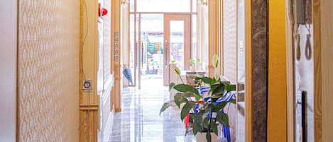 A hallway with marble flooring, a chandelier, and a potted plant.
