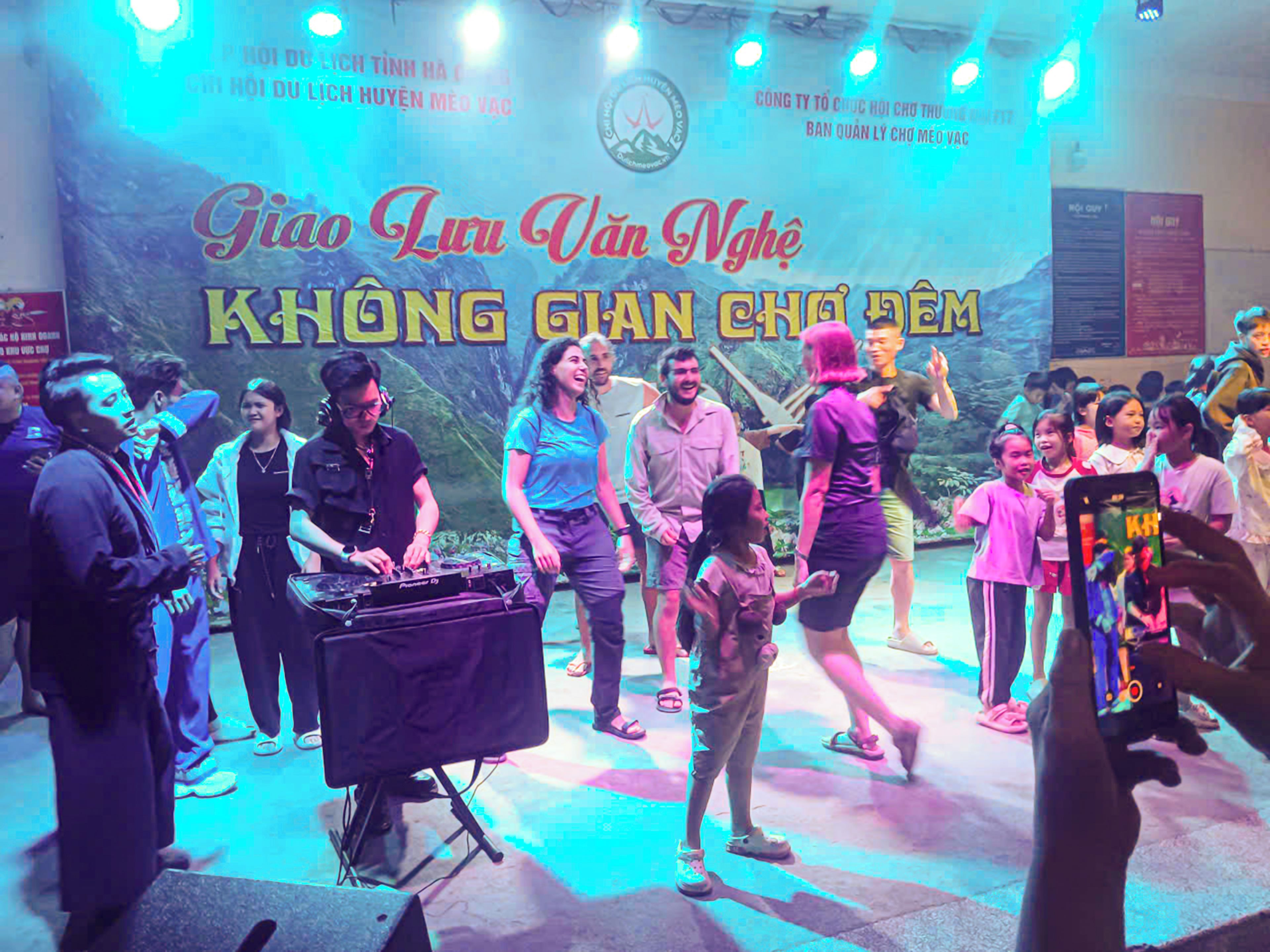 A group of people on a stage with a backdrop featuring text and a logo.