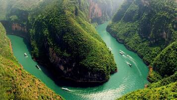 Un río serpentea por un valle exuberante y verde, con barcos en el agua.