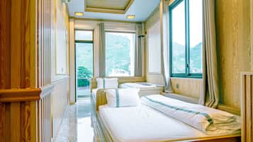 Une chambre d’hôtel avec un lit, une fenêtre avec des rideaux, un plafond doté d’un éclairage encastré et une vue sur l’extérieur.