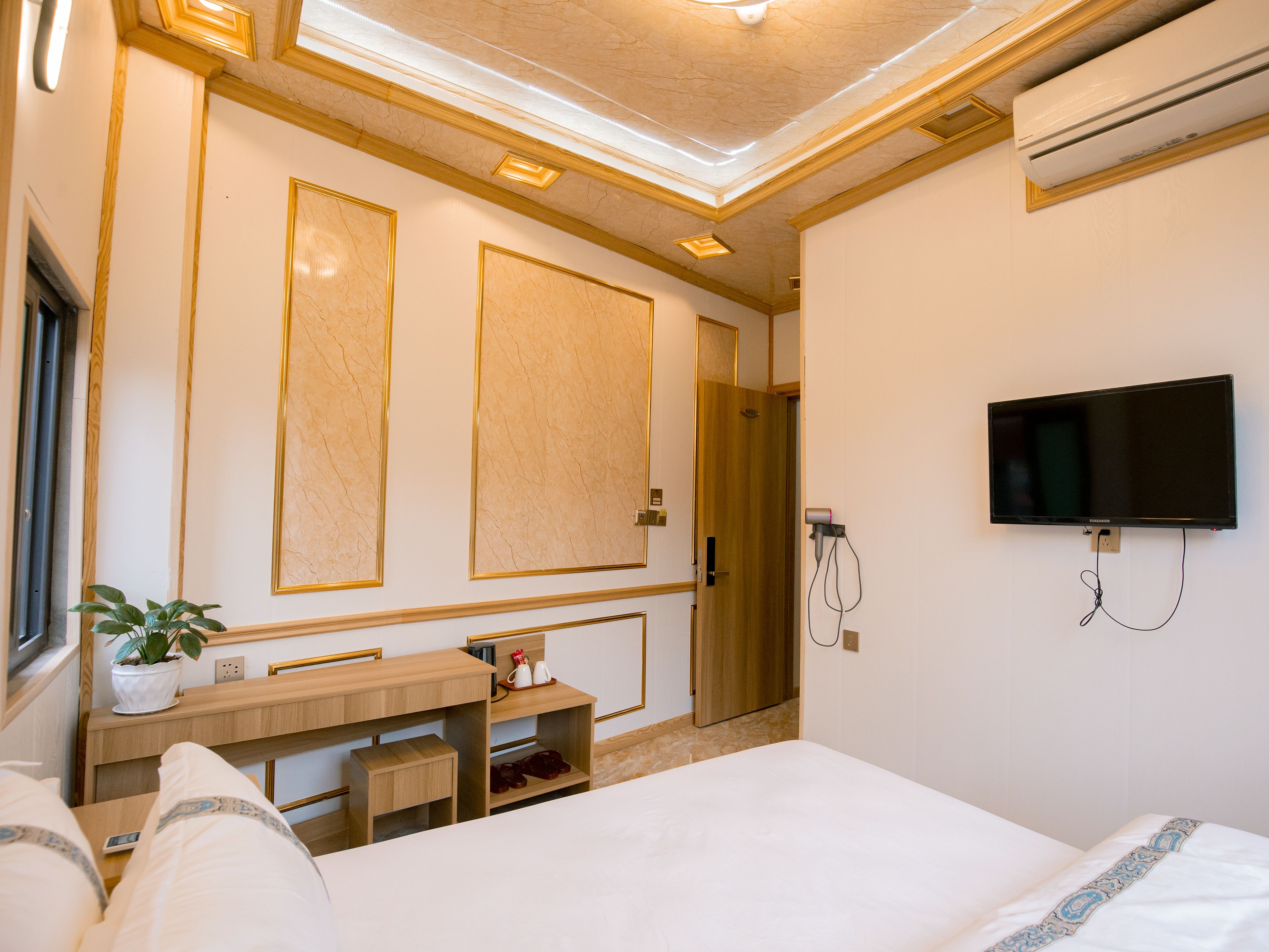 A hotel room with a bed, a desk, a TV, and a shower.