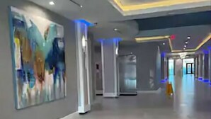 Un hall d’entrée spacieux au design moderne, agrémenté d’un grand tableau abstrait sur le mur de gauche et d’un sol à motifs.