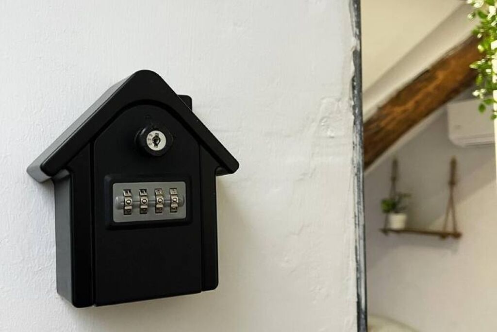 A black intercom mounted on a white wall with a keypad.