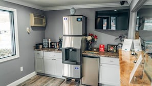 Cozinha com dispensador de água embutido, geladeira e bancada com cafeteira e objetos decorativos.