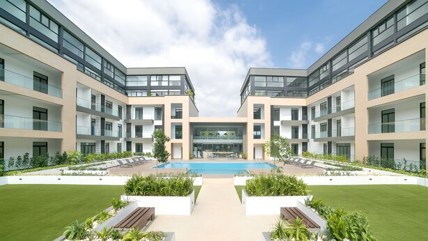 Ein modernes Gebäude mit Innenhof, Außenbestuhlung und Schwimmbad.