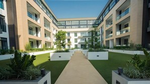 Ein modernes Gebäude mit einem zentralen Innenhof, umgeben von Balkonen und großen Fenstern.