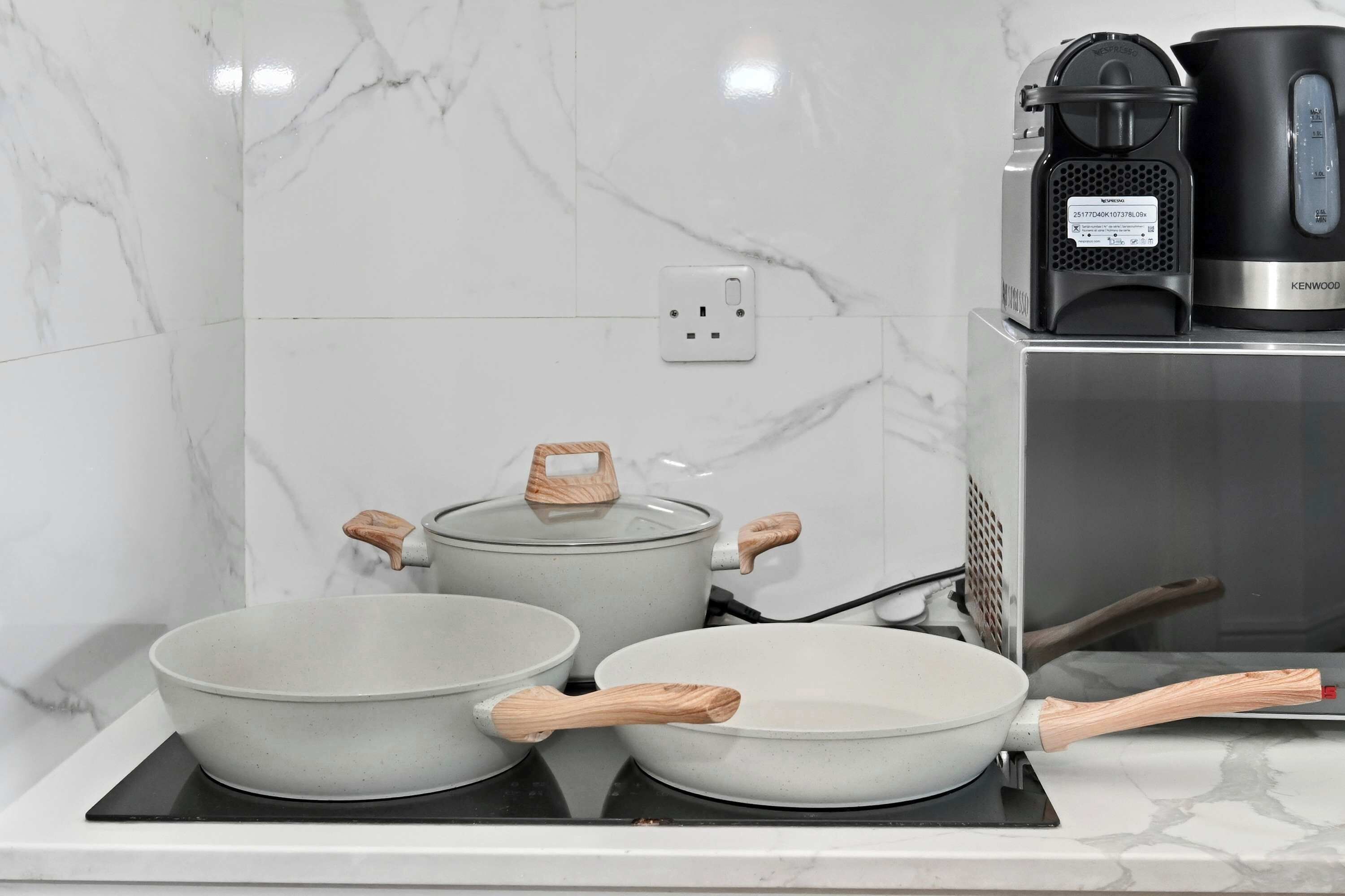 A kitchen with a stove, pots, and a coffee maker on a countertop.