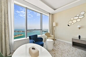 A modern hotel room with a large window offering a view of a coastal cityscape.