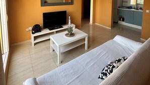 A living room with a TV, a white sofa, a coffee table, and a kitchen visible through an open doorway. - Bungalow with pool, private patio of 17m2 and terrace (Playa del Carabassi) (Gran Alacant)
