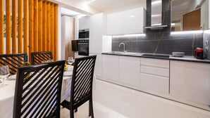 Una cocina moderna con armarios blancos, encimera negra y separador de madera.
