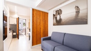 Una sala de estar moderna con un sofá azul, un separador de listones de madera y un cuadro de una gran formación rocosa en la pared.