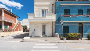 Un hotel con fachada blanca, nivel superior azul y una escalera que conduce a la entrada.