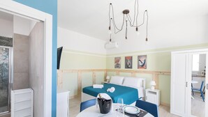 Una habitación de hotel con cama, mesita de noche y un rincón comedor con una mesa para dos.