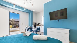 Una habitación de hotel moderna con una cama grande, un escritorio y una kitchenette.