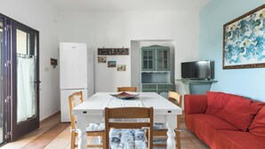 A dining area with a white table, wooden chairs, and a red sofa.