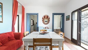 A dining area with a white table, red curtains, and a decorative wall piece.