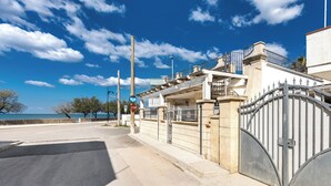 A gated entrance with a metal gate, a stop sign, and a clear blue sky.