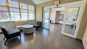 A lobby with a seating area, a reception desk, and an exit sign. - Permian Studio Apartments (Monahans)