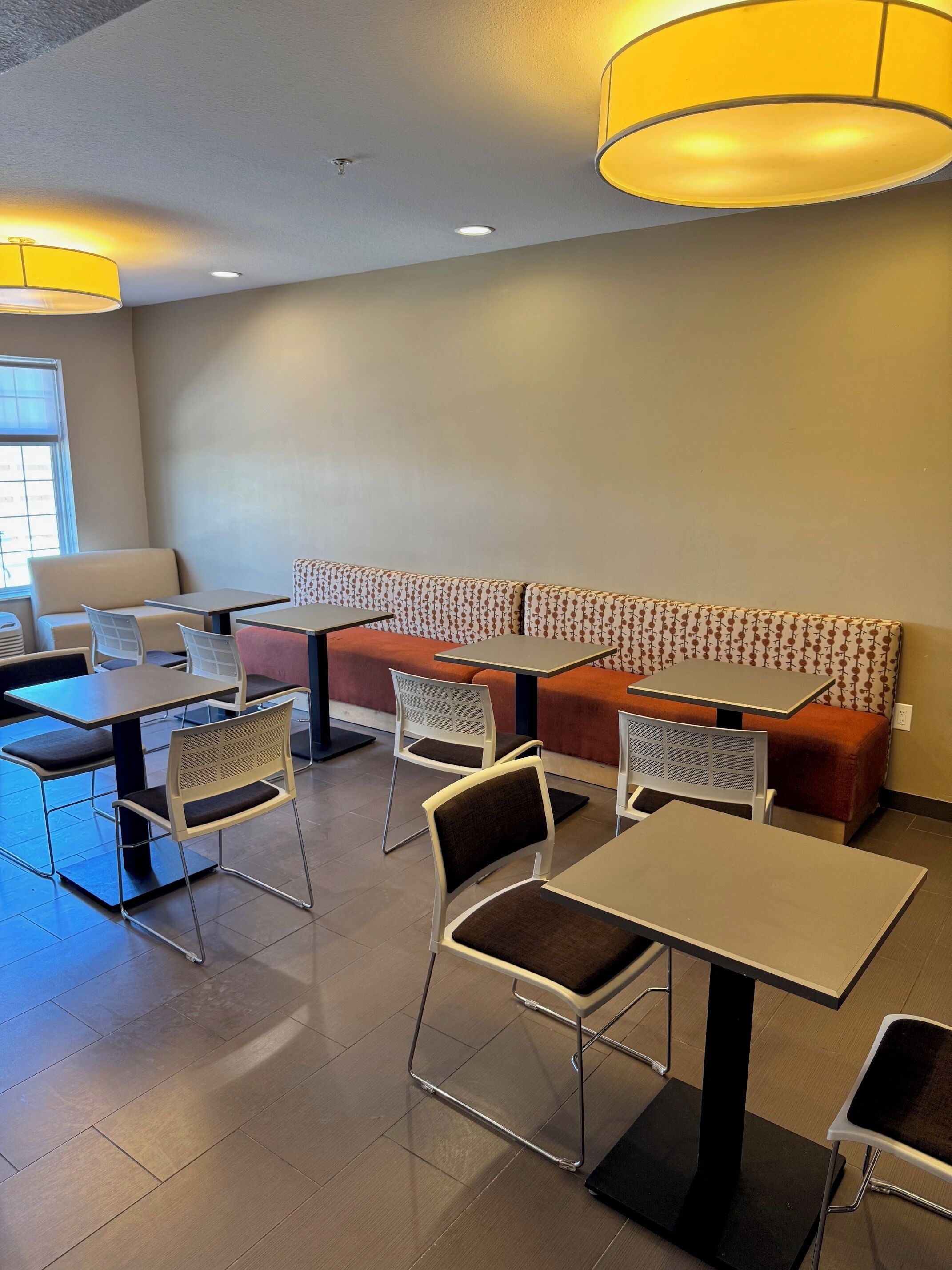 Un café moderno con diversas opciones de asientos, incluyendo mesas y un banco con diseño.