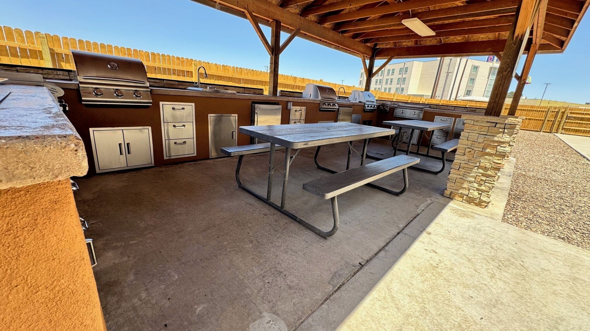 Une terrasse extérieure équipée d’un barbecue, d’un évier et d’une table de pique-nique.