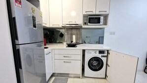 Una cocina compacta con refrigerador, microondas, lavaplatos y lavadora.