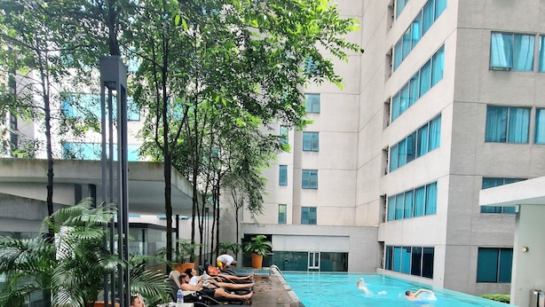 Zona de piscina con sillas de descanso y plantas en macetas.