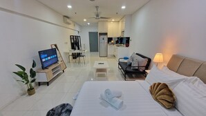Una habitación de hotel moderna con cama, televisor, escritorio y kitchenette.