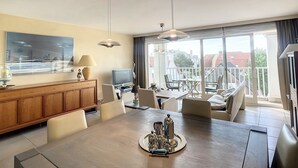 A modern dining area with a large table, chairs, and a television. - Apartment Near Belgian Coast With Terrace (Knokke-Heist)