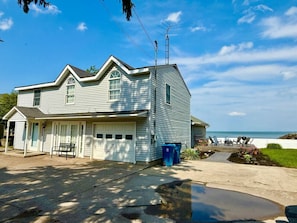 A two-story house with a garage, a porch with a bench, and a view of the ocean. - Waterfront Beach Home-3Bdrms/2Bth-close to everything! (Huron)
