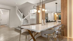 A modern kitchen with a white marble countertop, gold accents, and pendant lighting. - 5 BD/ 4.5 BA/ Windsor Cay (16053 BW) (Clermont)