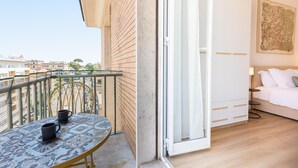 A balcony with a table and chairs, a sliding glass door leading to a bedroom with a bed and a nightstand. - Apartment in Via di Santa Costanza, a short distance from Corso Trieste (Rome)