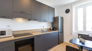 A modern kitchen with grey cabinets, a stainless steel refrigerator, a microwave, and an oven. There is a sink with a faucet, a coffee maker, and a clock on the wall. - Apartment in Via di Santa Costanza, a short distance from Corso Trieste (Rome)
