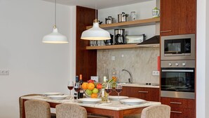 A modern kitchen with wooden cabinets, a built-in oven, and a dining area with a marble table and chairs.