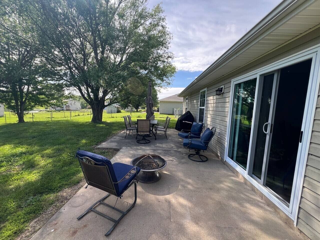 An outdoor patio area with a fire pit, seating, and a covered grill.