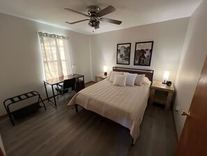 A bedroom with a bed, a desk, a chair, a ceiling fan, and two bedside lamps. - Relax Enjoy Mid-Missouri with Fenced in Back Yard (Boonville)