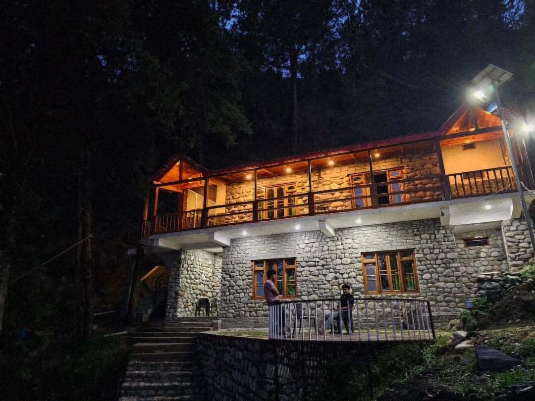 A stone building with a balcony and a staircase leading to the entrance.
